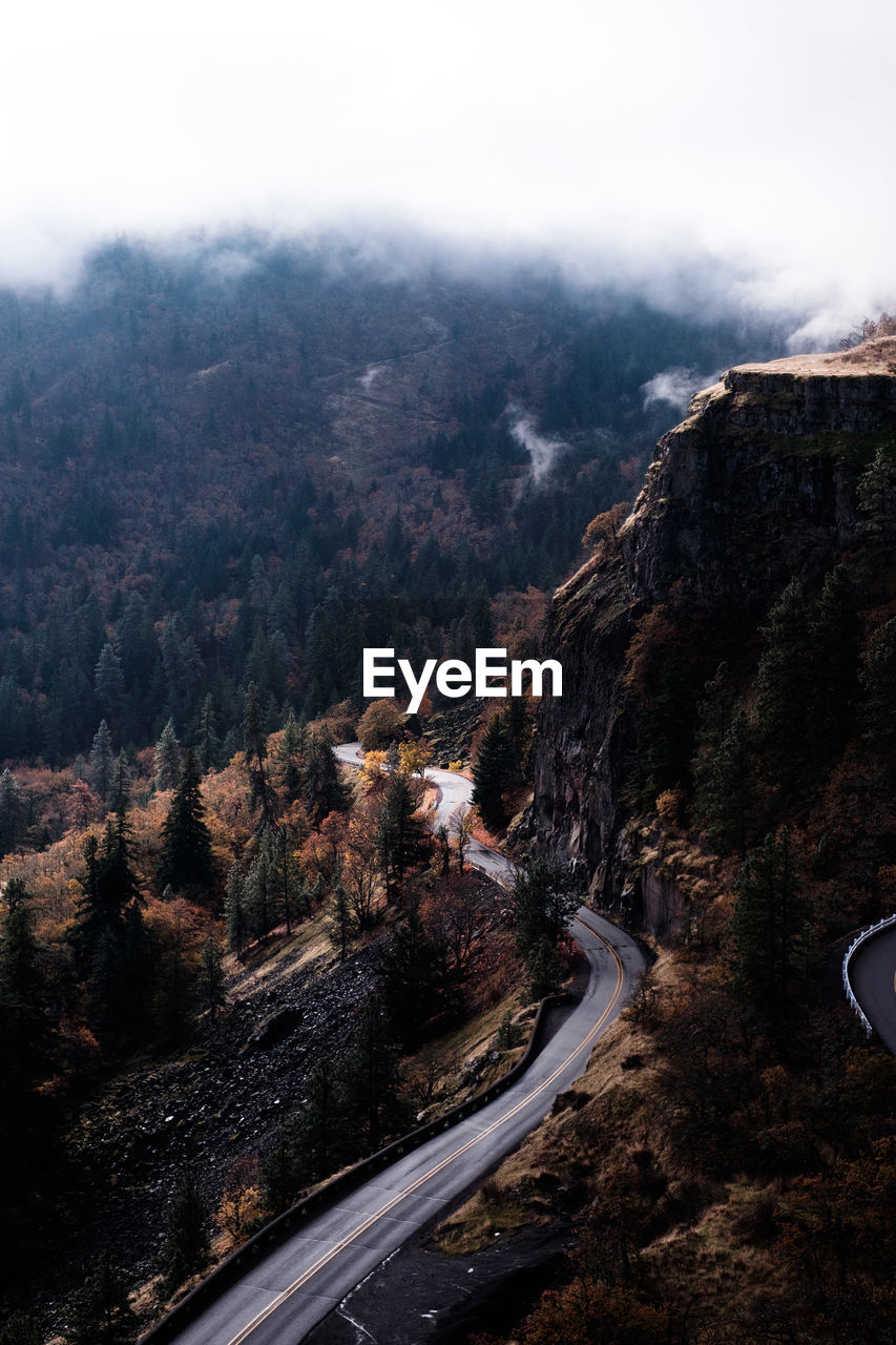 High angle view of road by mountain against sky during foggy weather