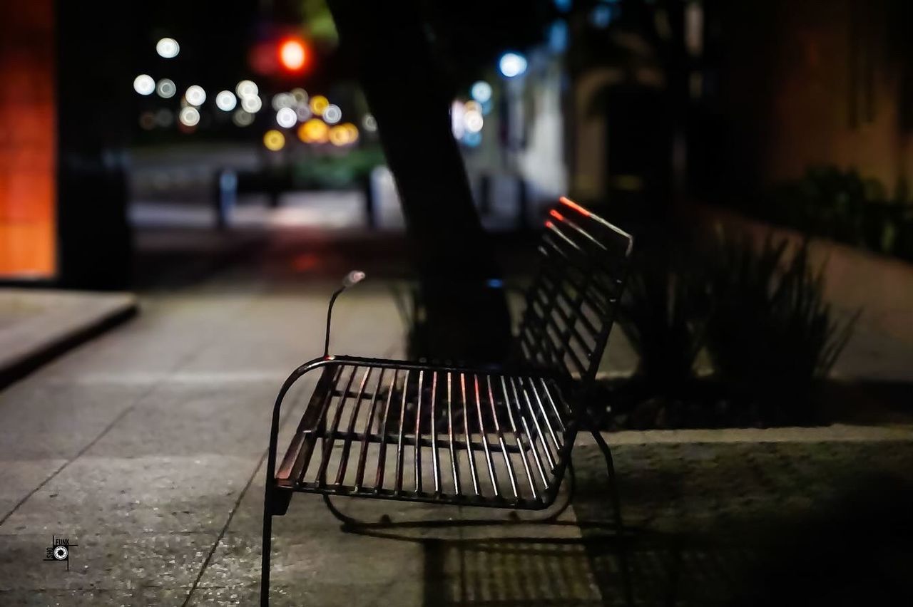 night, darkness, light, illuminated, city, street, architecture, seat, evening, lighting, footpath, absence, no people, empty, outdoors, focus on foreground, sidewalk, chair