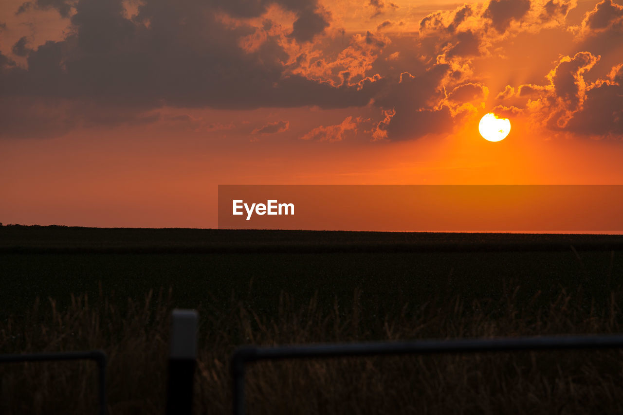 Scenic view of field against orange sky