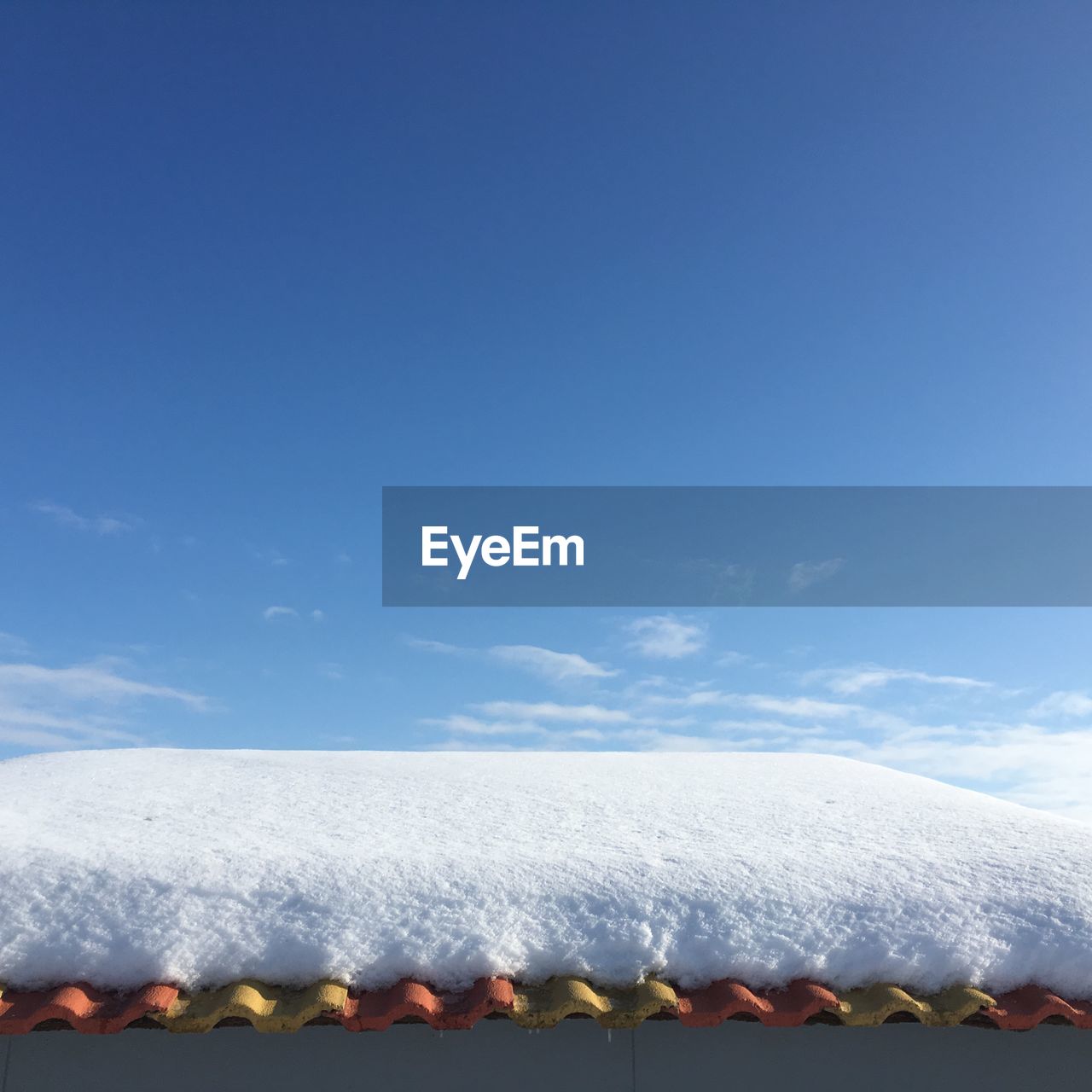 Snow covered roof against blue sky