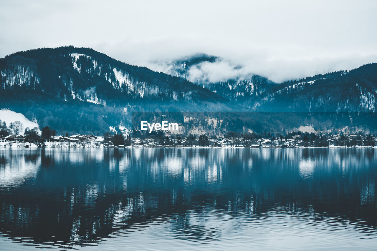 Scenic view of lake by snowcapped mountains against sky