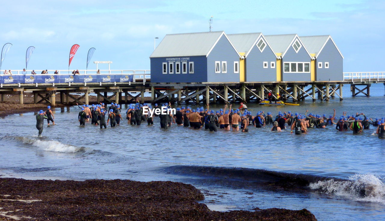 GROUP OF PEOPLE ON BEACH AGAINST SEA