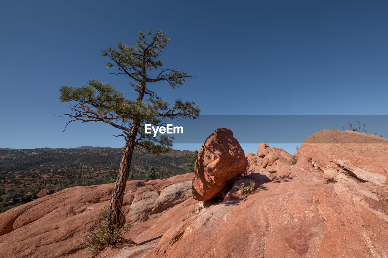 Rock formations on landscape against clear blue sky