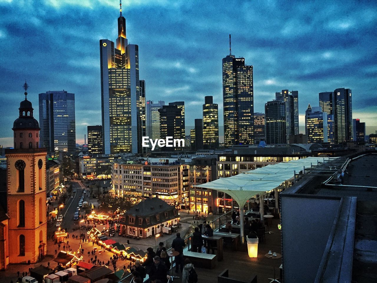 Illuminated skyscrapers against cloudy sky at dusk