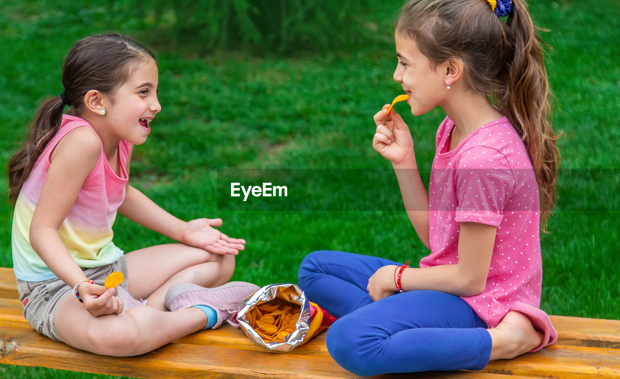 Side view of mother and daughter sitting at park