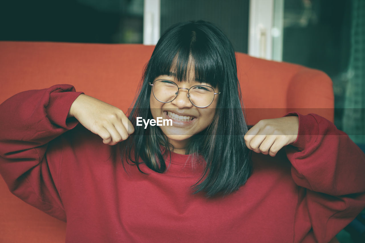 Toothy smiling face of asian teenager at home living room