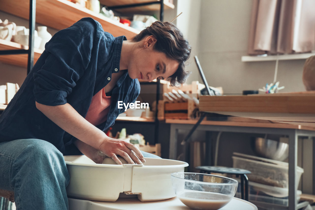 A woman in a pottery workshop works on a potter's wheel