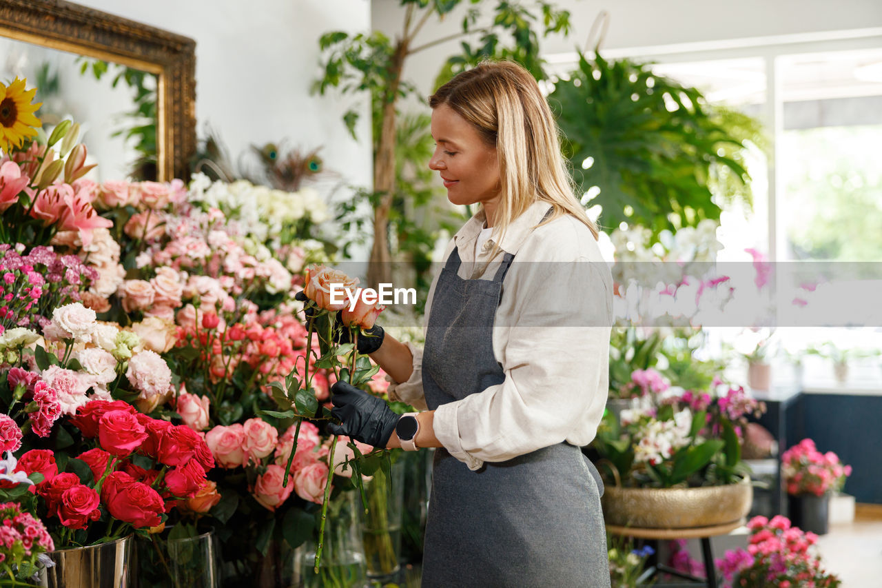 portrait of young woman standing by flowers