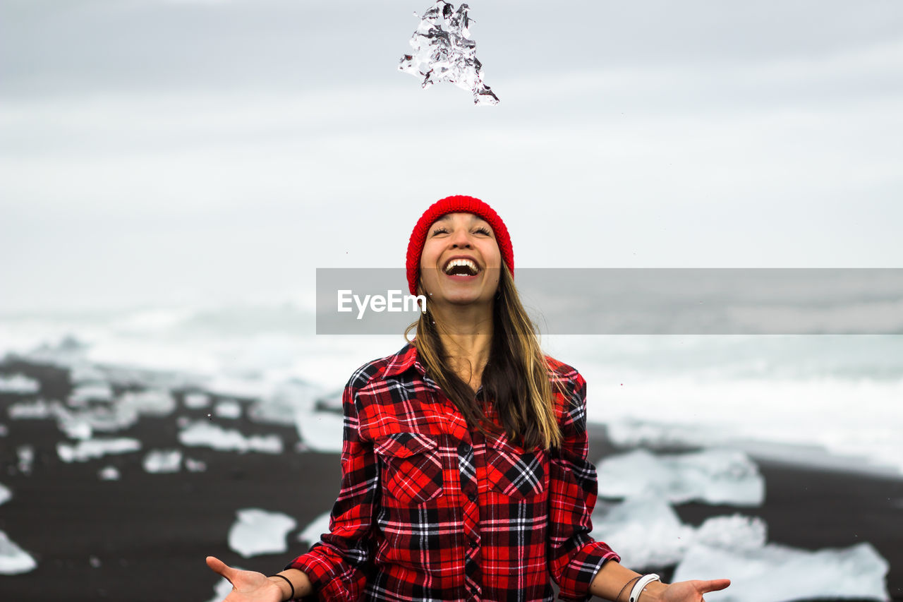 Cheerful woman standing at beach during winter