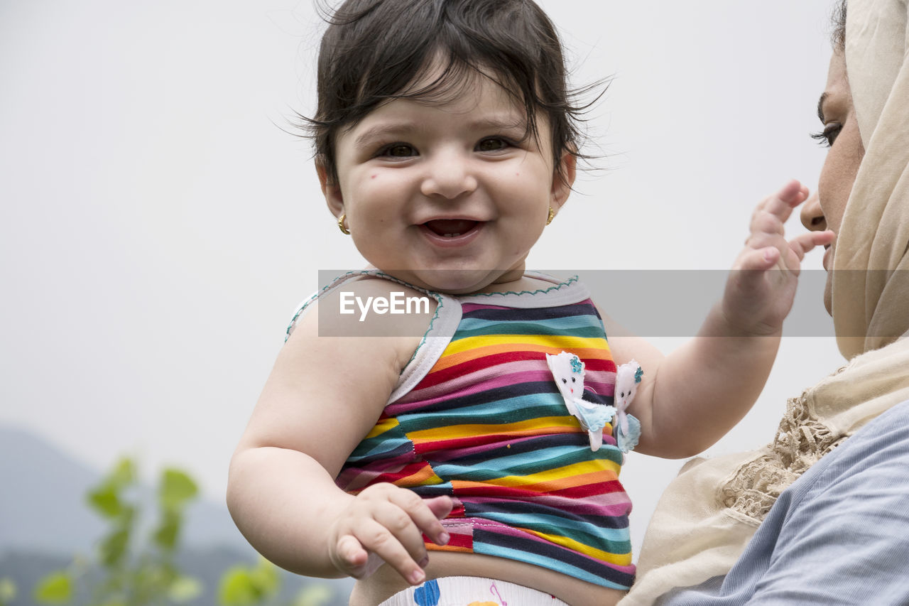 Mother holding baby against sky