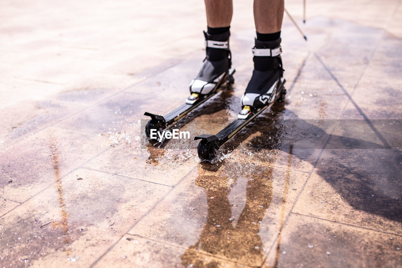 Low section of person inline skating on wet tiled floor