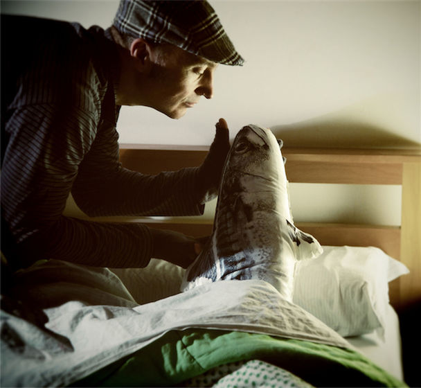 Side view of man putting replica of fish in bed