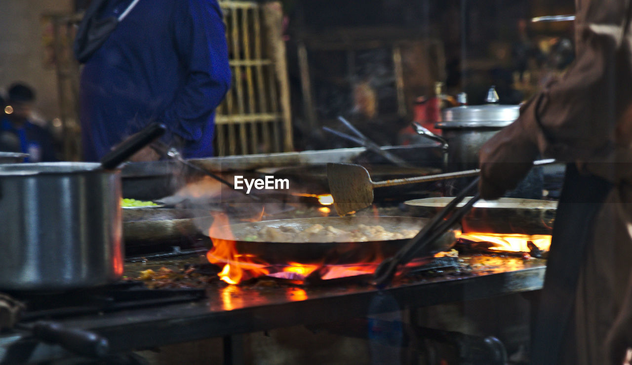 Midsection of people preparing food in kitchen