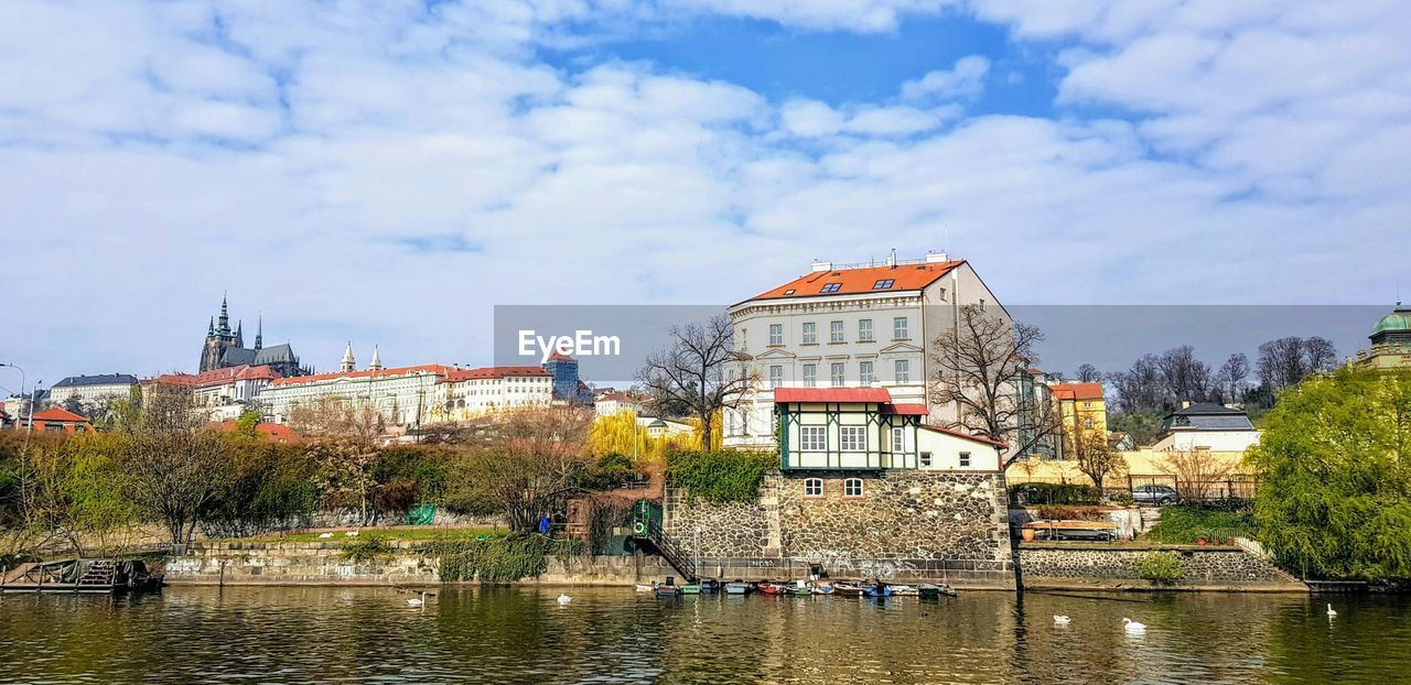 Buildings by river vltava against sky