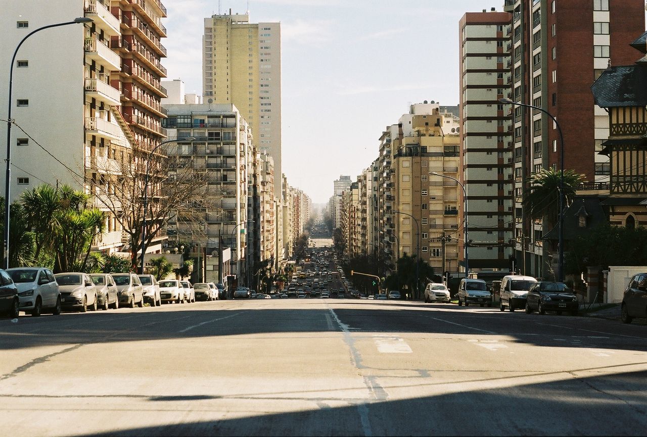 City street by modern buildings against sky