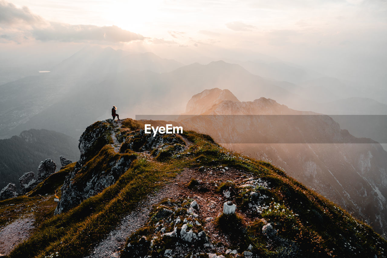 rear view of man standing on mountain against sky