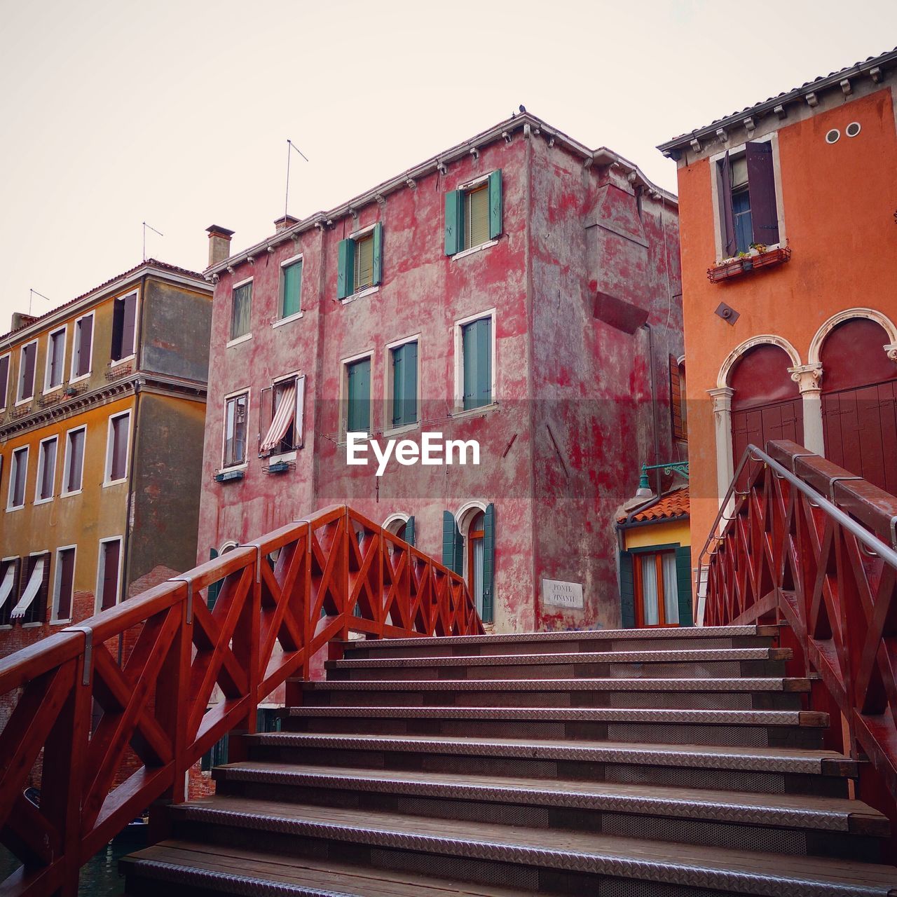 Steps by old buildings in town against sky