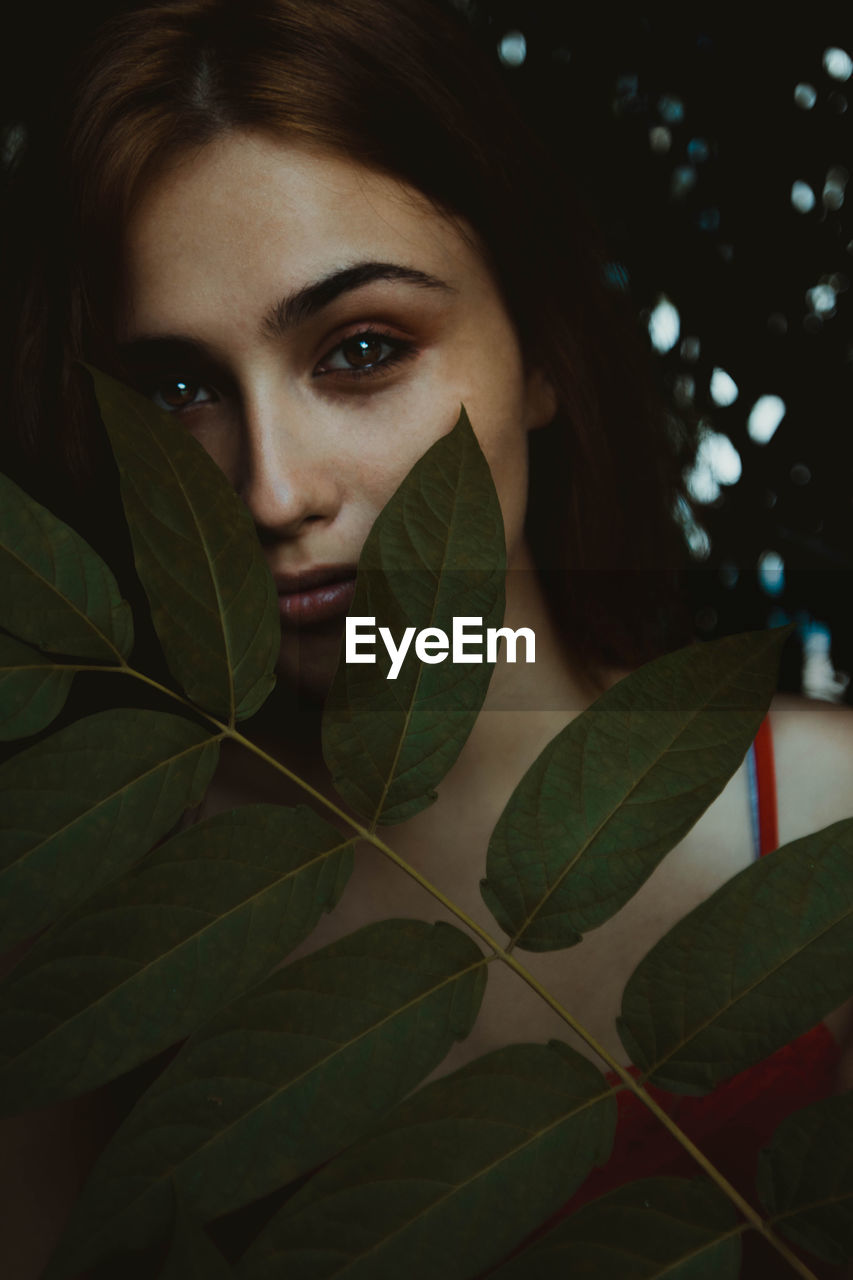 Close-up portrait of young woman with leaves