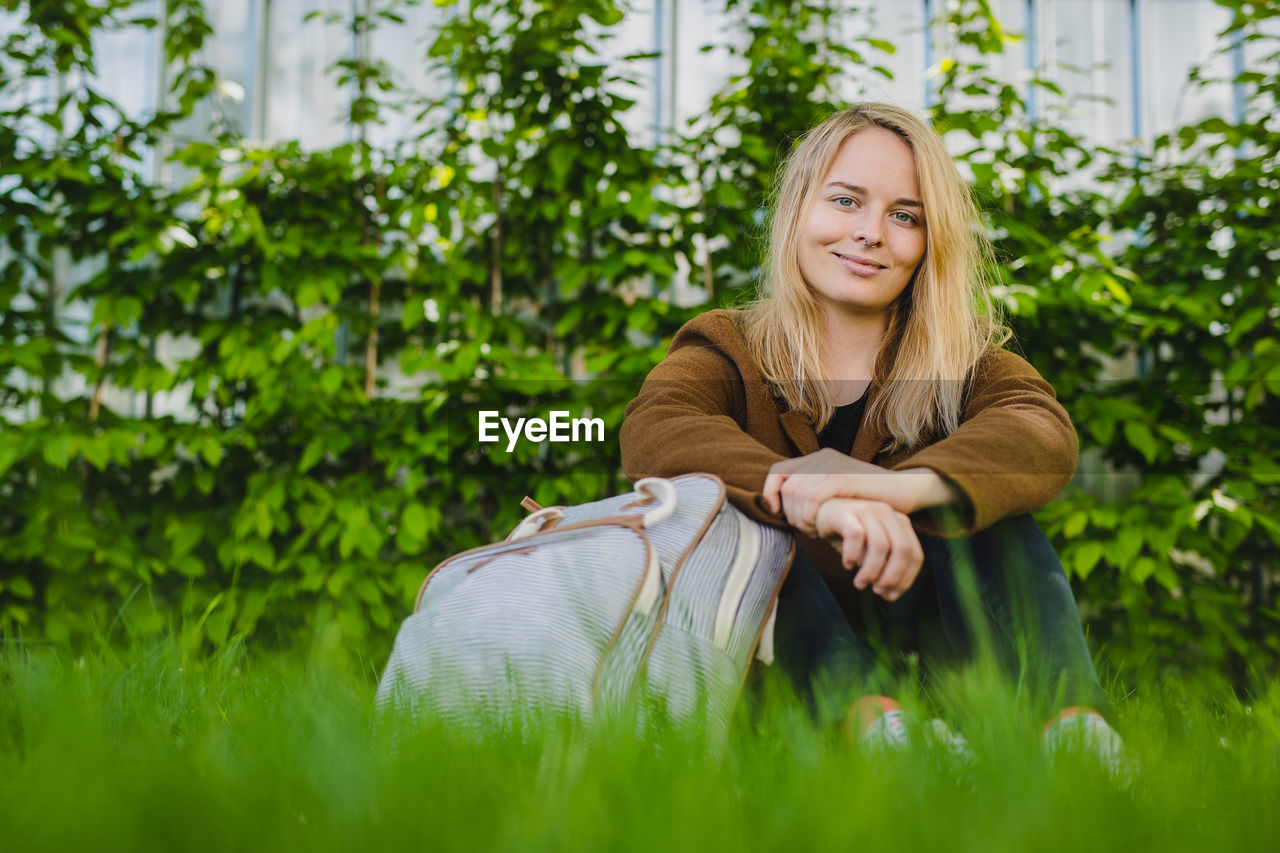 Portrait of smiling young woman with blond hair sitting on grass