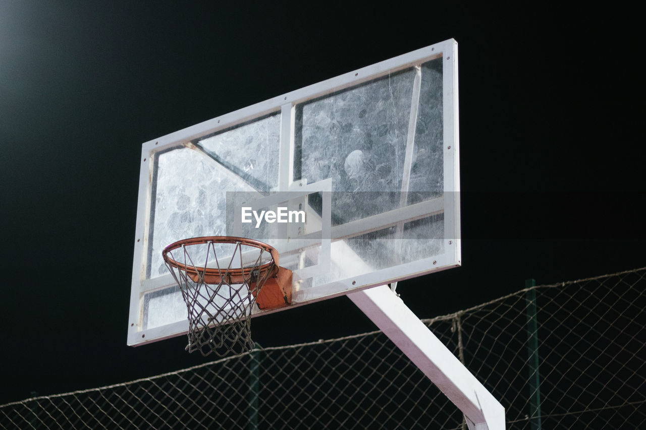 Low angle view of basketball hoop against black background