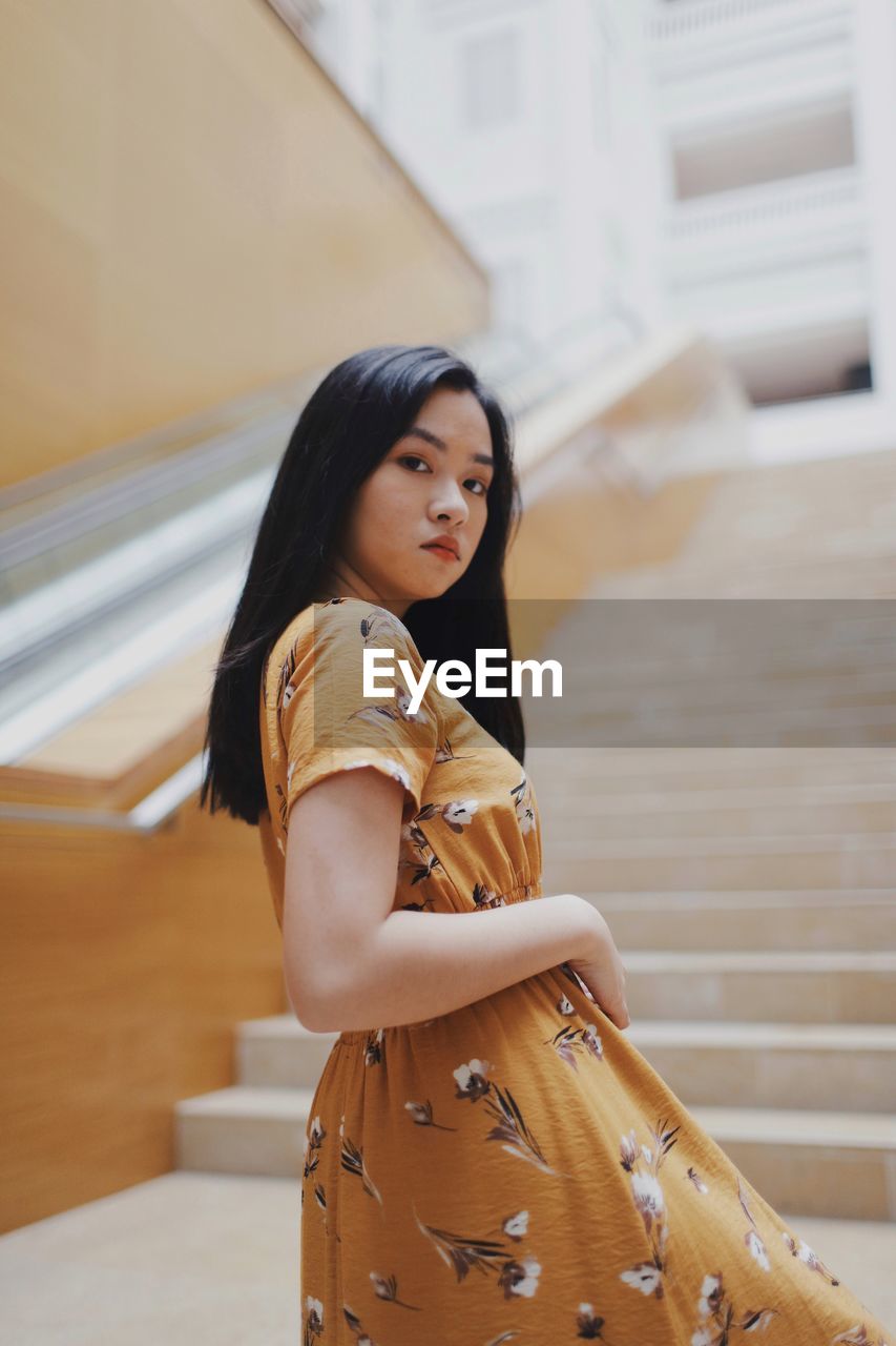 Low angle view portrait of beautiful young woman standing on staircase