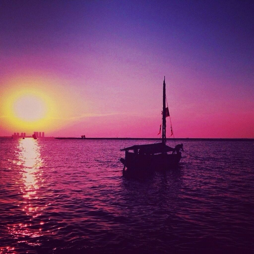 Silhouette boat in lake against purple sky