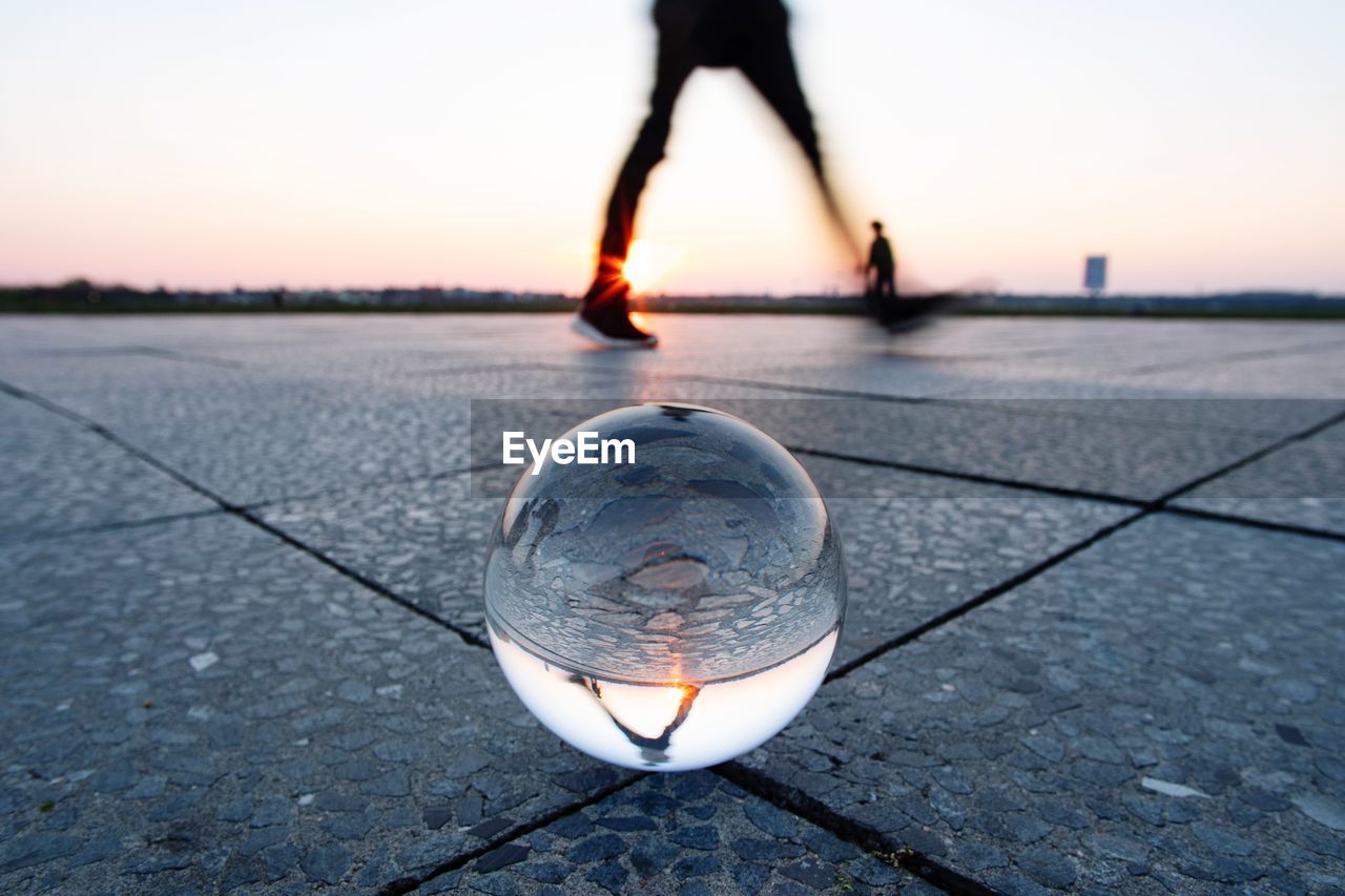 Low section of person walking by crystal ball on footpath