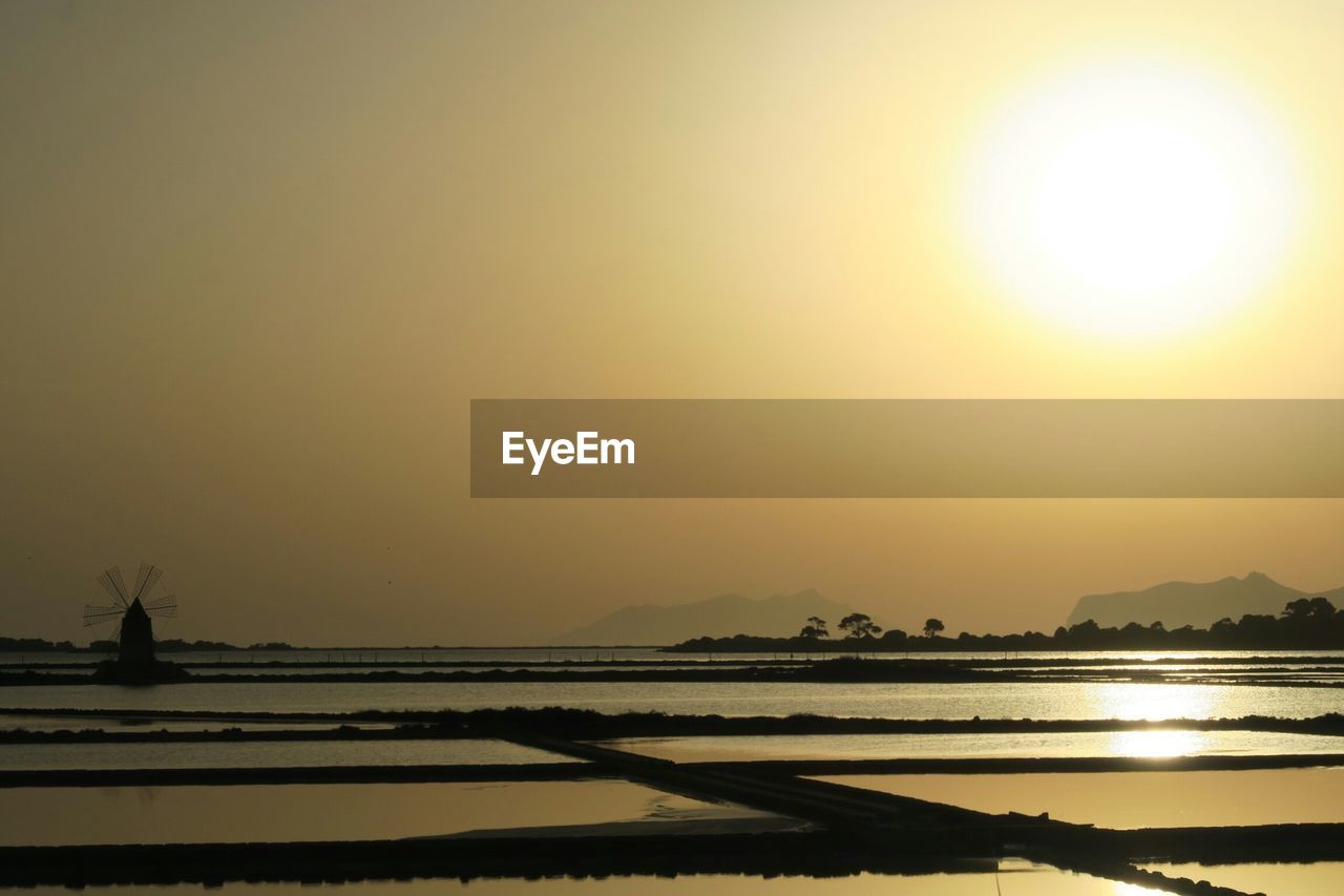 Scenic view of salt flat against sky during sunset