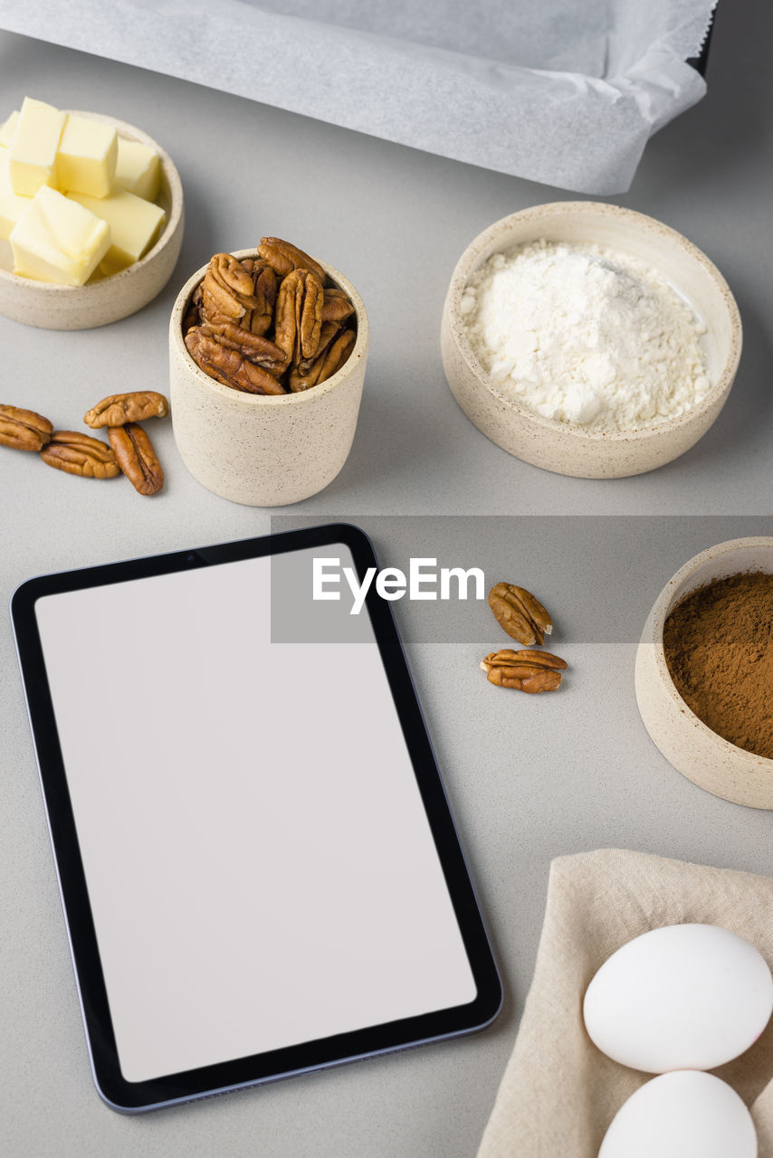 Close-up of brownie ingredients and tablet on a gray surface in the modern kitchen. culinary blog.