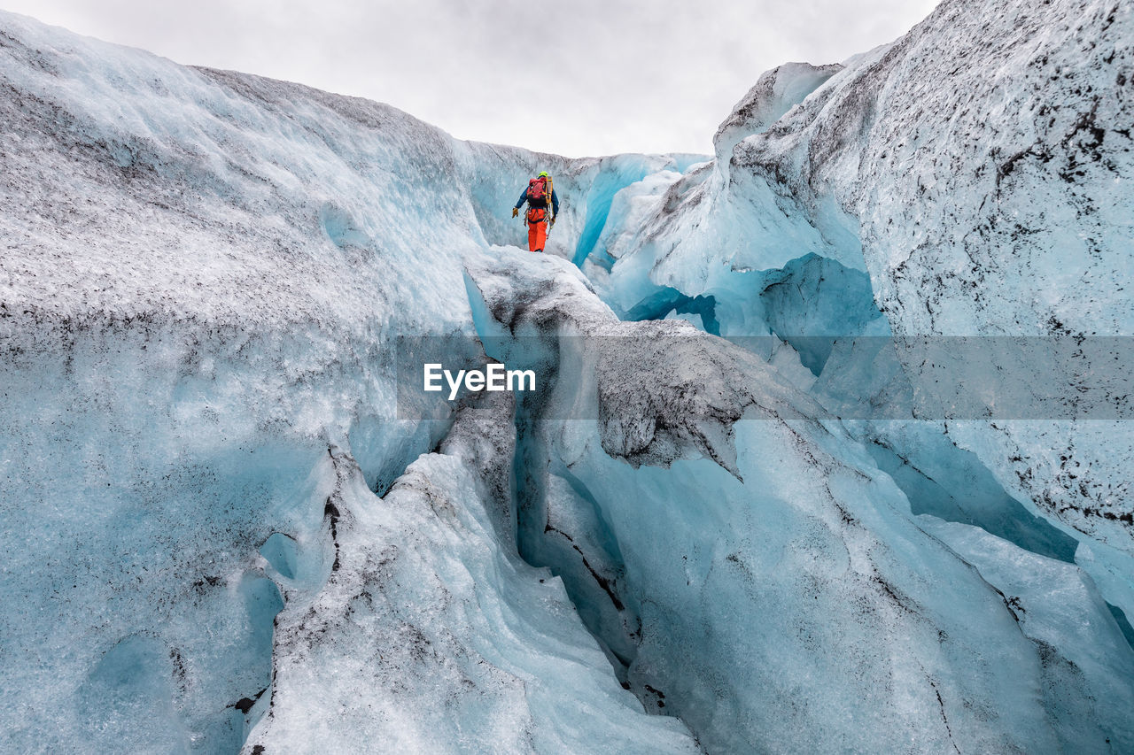 Low angle view of hiker standing on snow formation