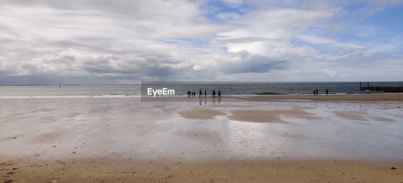 PEOPLE ON BEACH AGAINST SKY