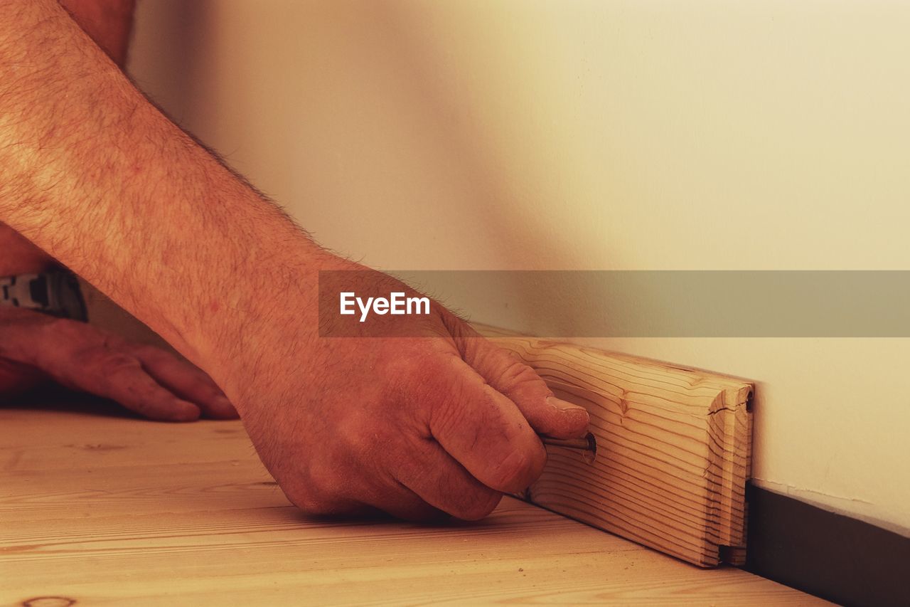 Cropped image of hands attaching wood on wall