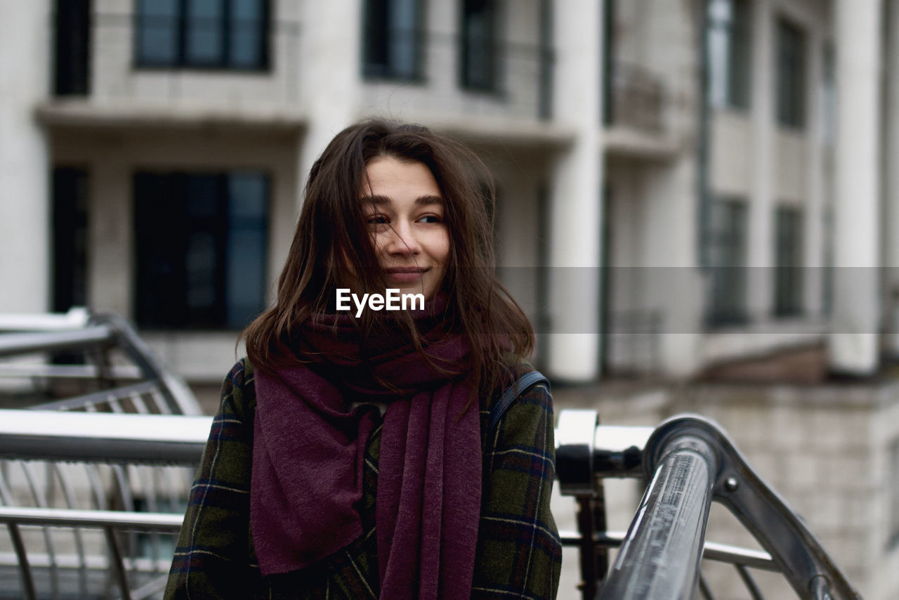 Portrait of beautiful young woman standing in the city and smiling