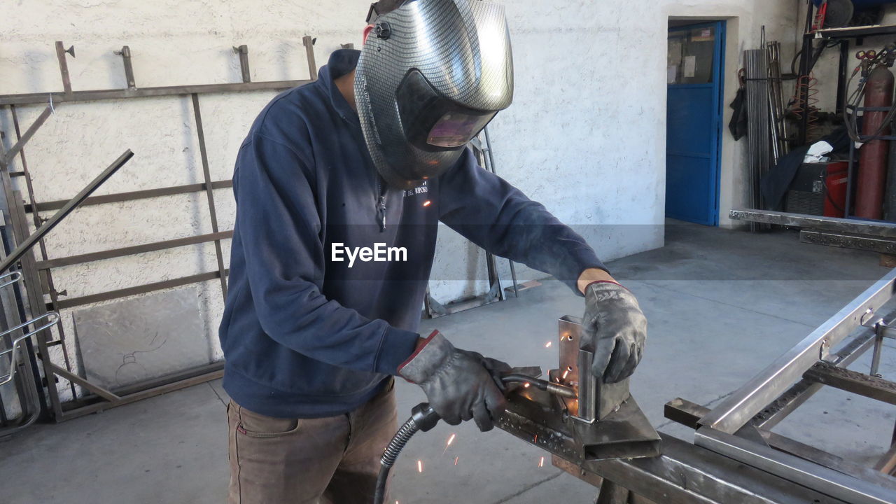 Worker welding metal at factory