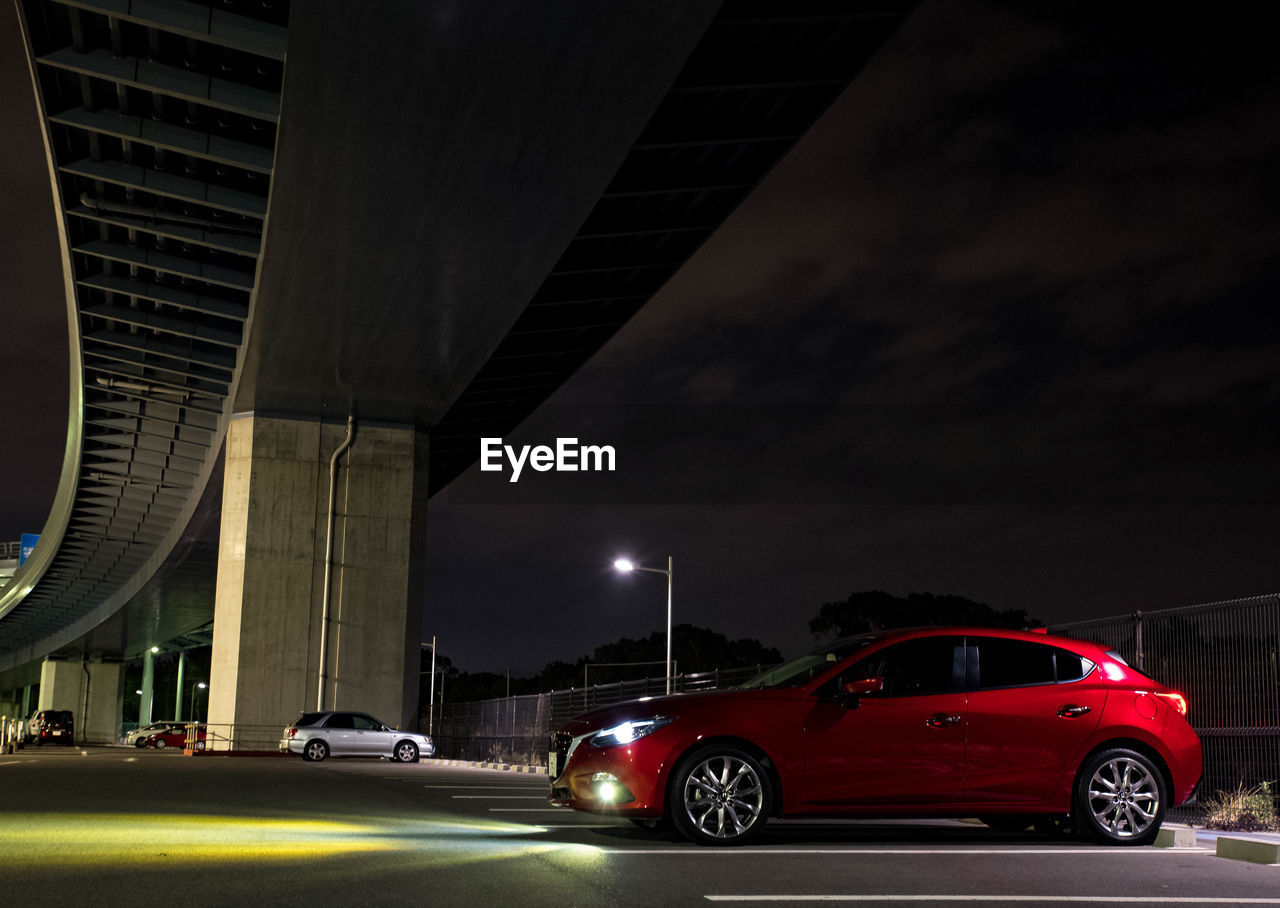 CAR IN ILLUMINATED CITY AT NIGHT