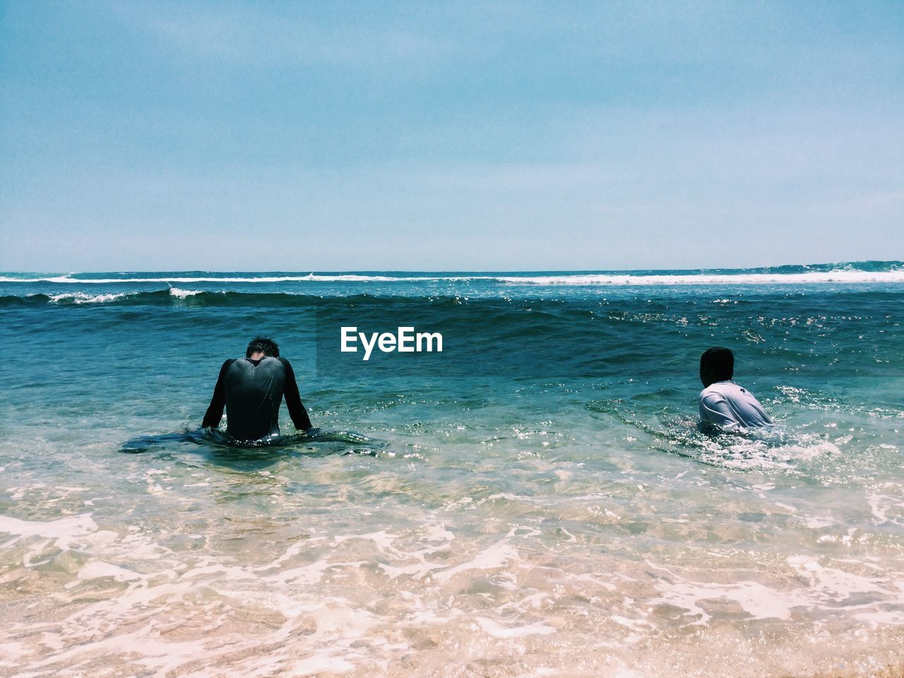 Boys swimming in sea against sky