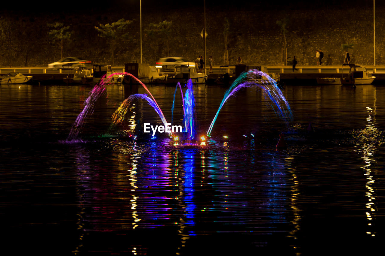 Illuminated bridge over river in city at night