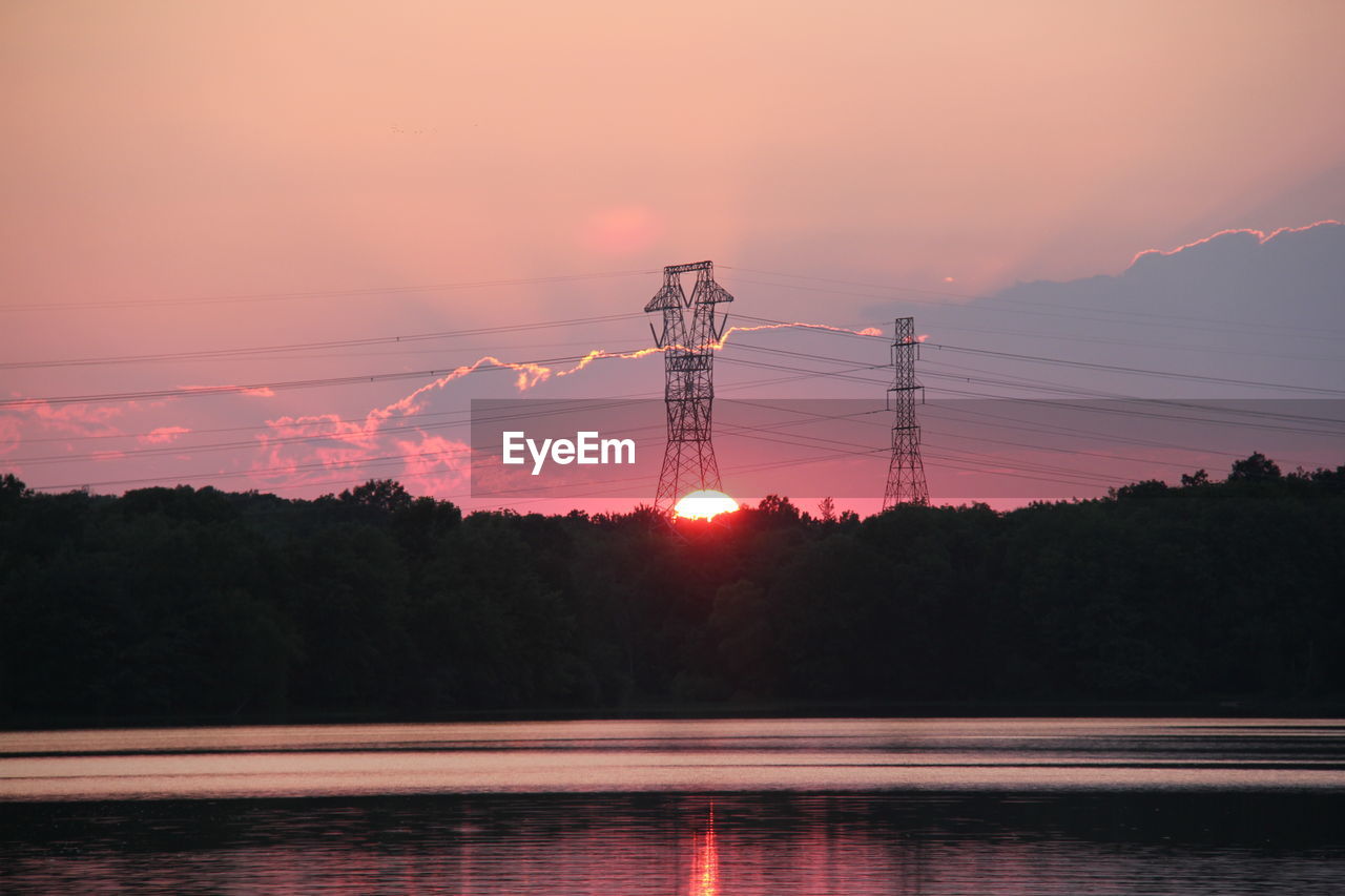 Scenic view of lake by trees against cloudy sky during sunset