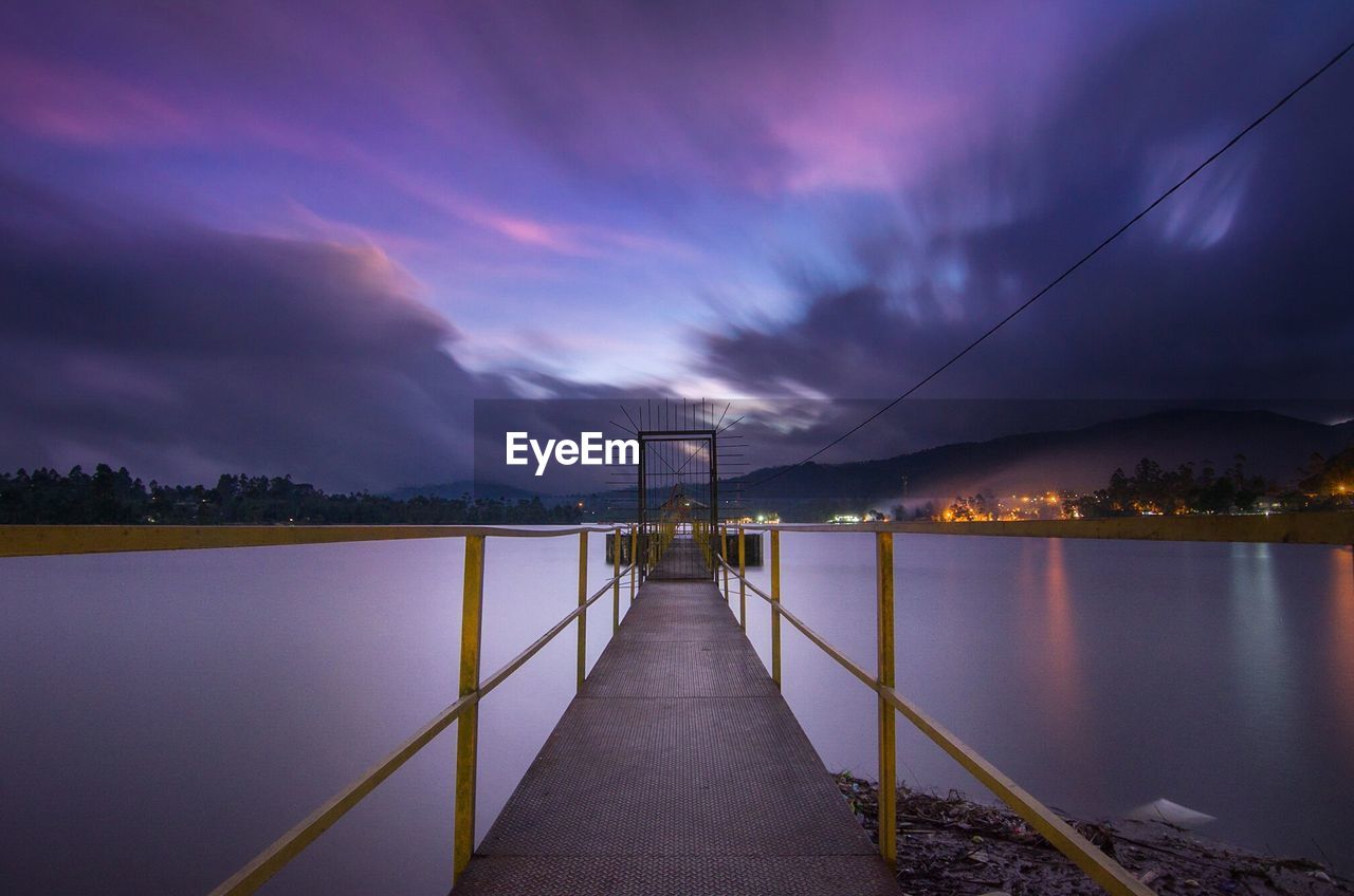 View of suspension bridge over river at sunset