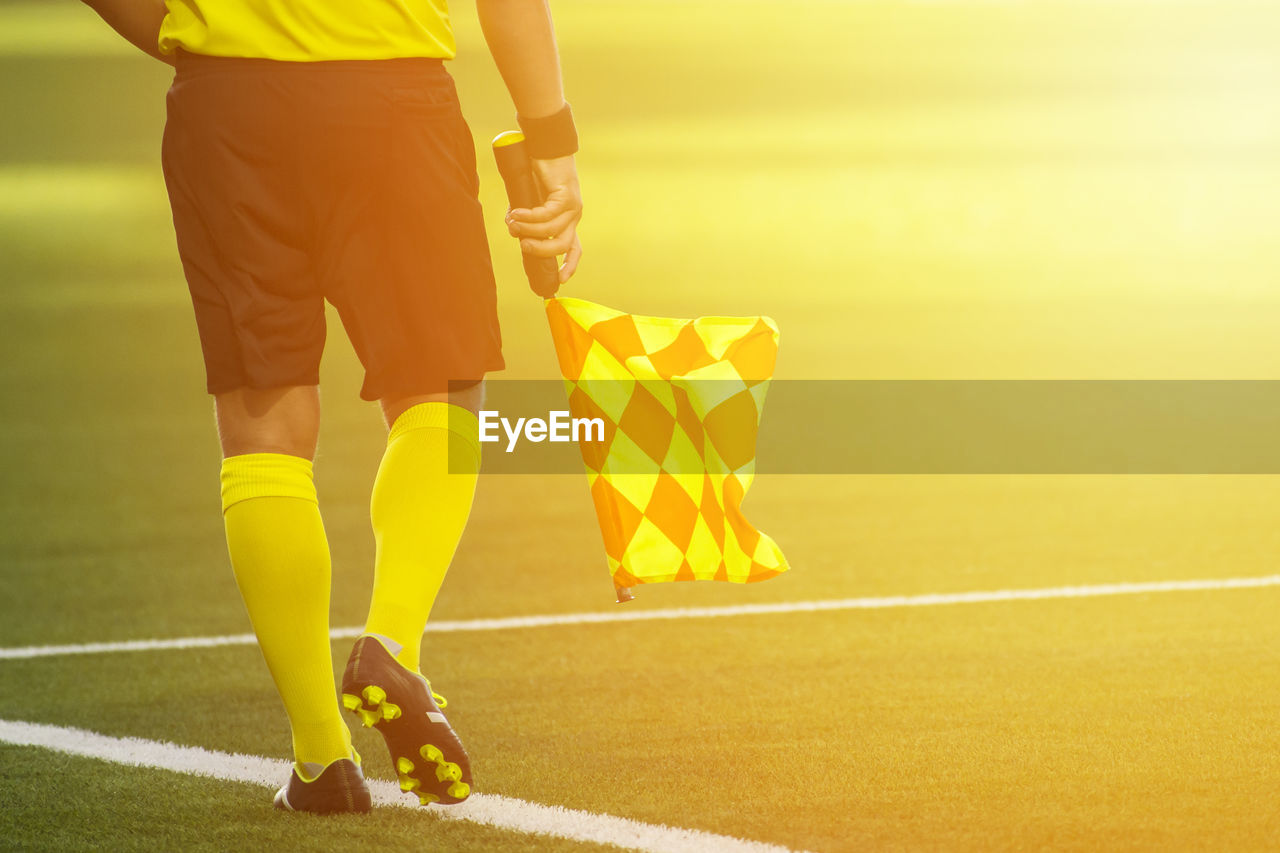 Low section of referee with flag walking on soccer field