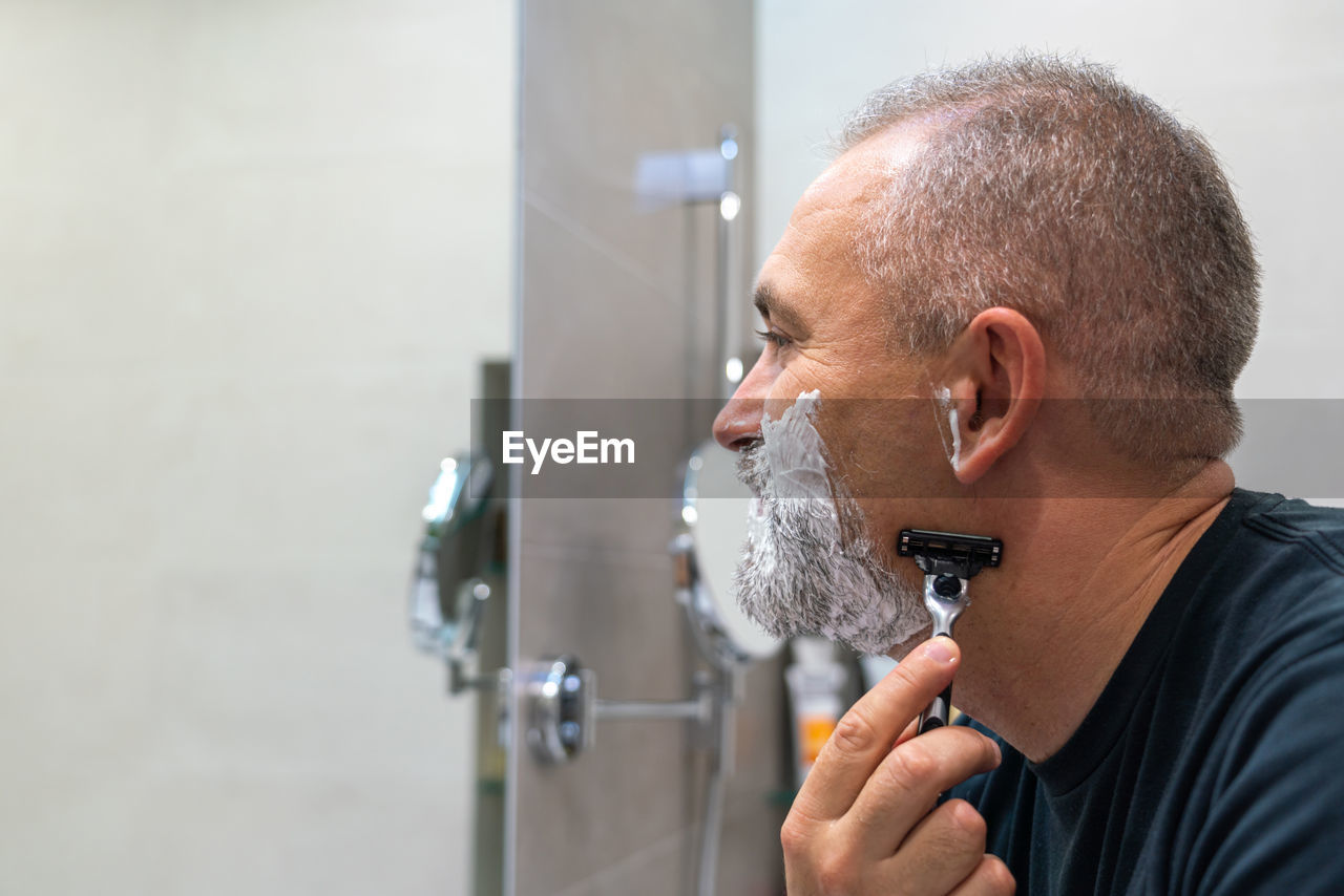 side view of man drinking water from faucet