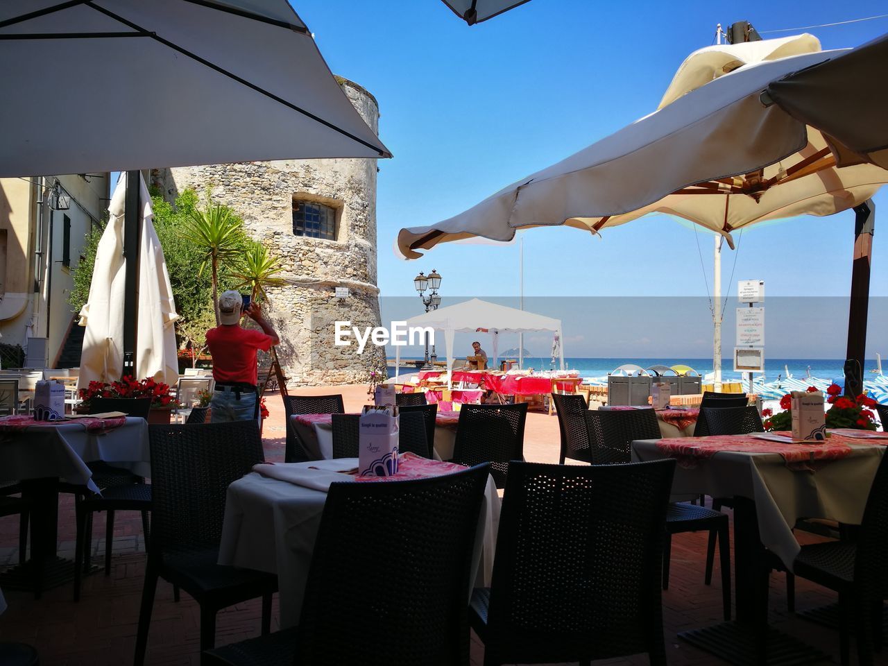 EMPTY CHAIRS AND TABLES AT RESTAURANT AGAINST SKY