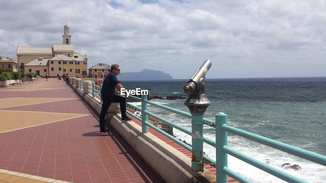 REAR VIEW OF WOMAN ON RAILING AGAINST SEA