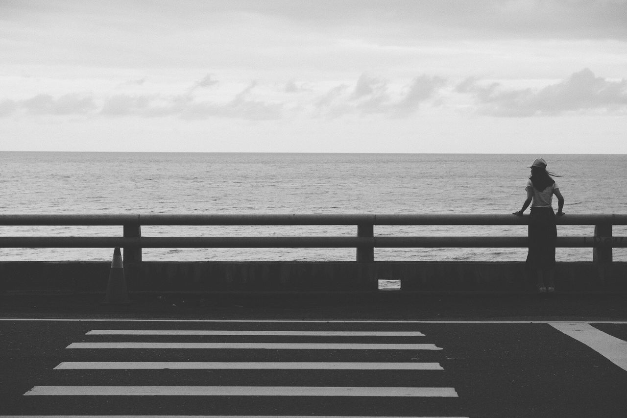 FULL LENGTH OF MAN STANDING ON RAILING AGAINST SEA