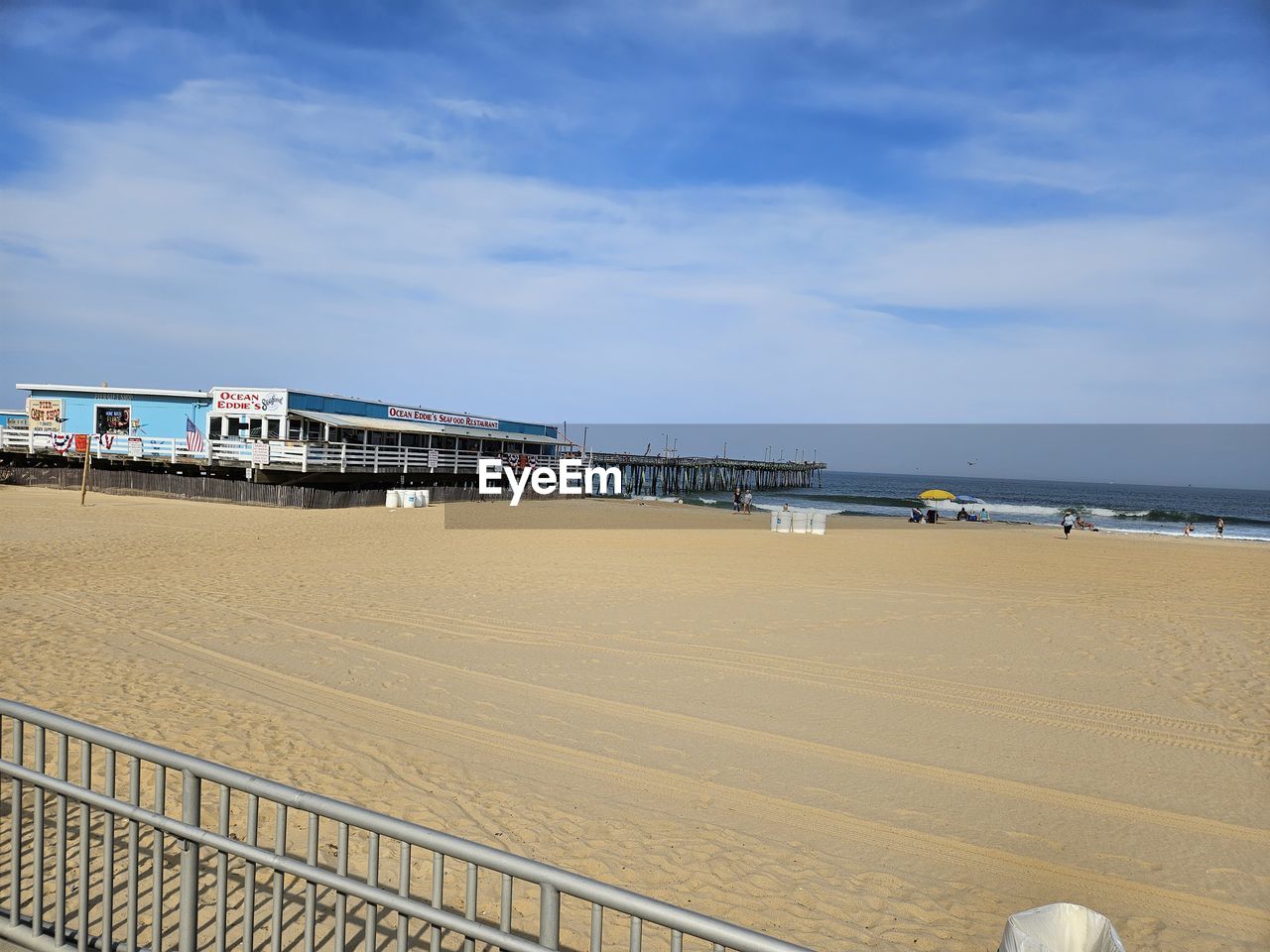 beach, sea, sky, water, land, walkway, sand, boardwalk, architecture, nature, coast, cloud, pier, built structure, ocean, vacation, shore, day, travel destinations, horizon over water, travel, holiday, tourism, body of water, trip, outdoors, railing, building exterior, hut, scenics - nature, lifeguard hut, beauty in nature, horizon, man made structure, no people, blue, coastline, transportation, tranquility, tranquil scene, water's edge