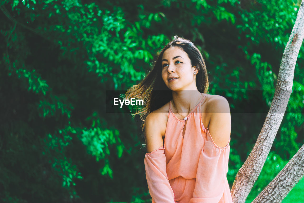 Young woman sitting on tree trunk