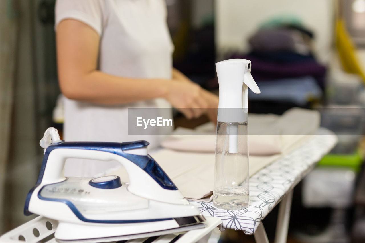 Housewife with bottle spray foggy for iron clothes on ironing board