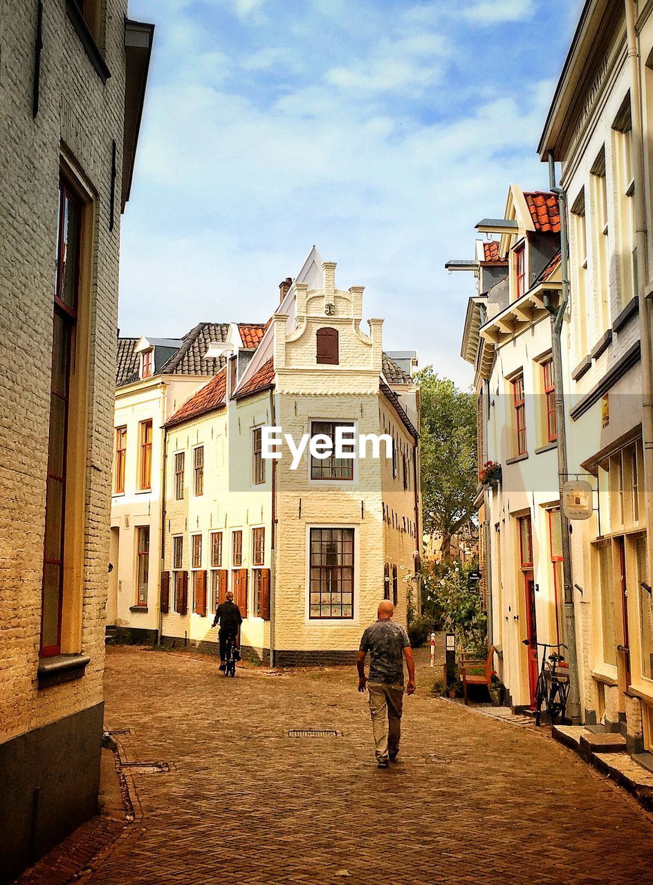 PEOPLE WALKING ON STREET AMIDST BUILDINGS