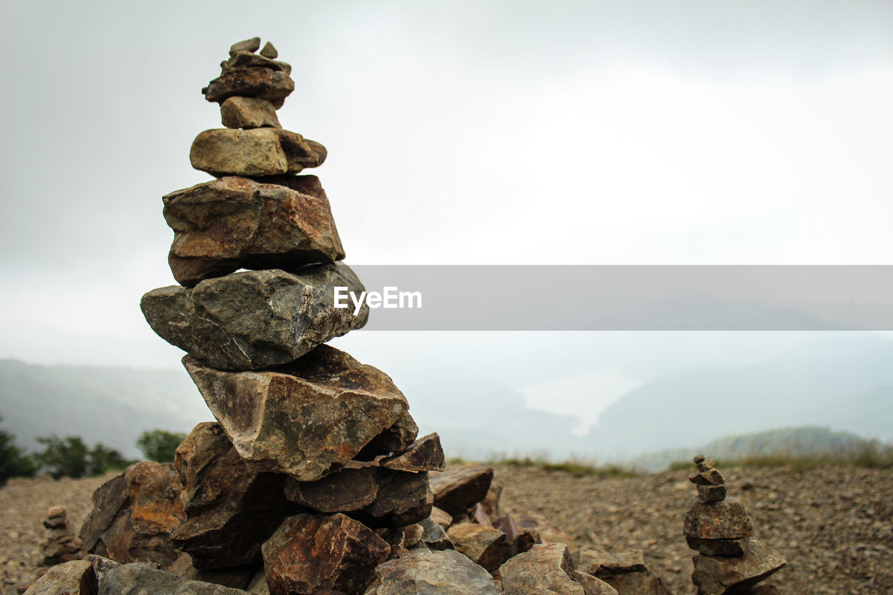 Stack of stones on field against sky