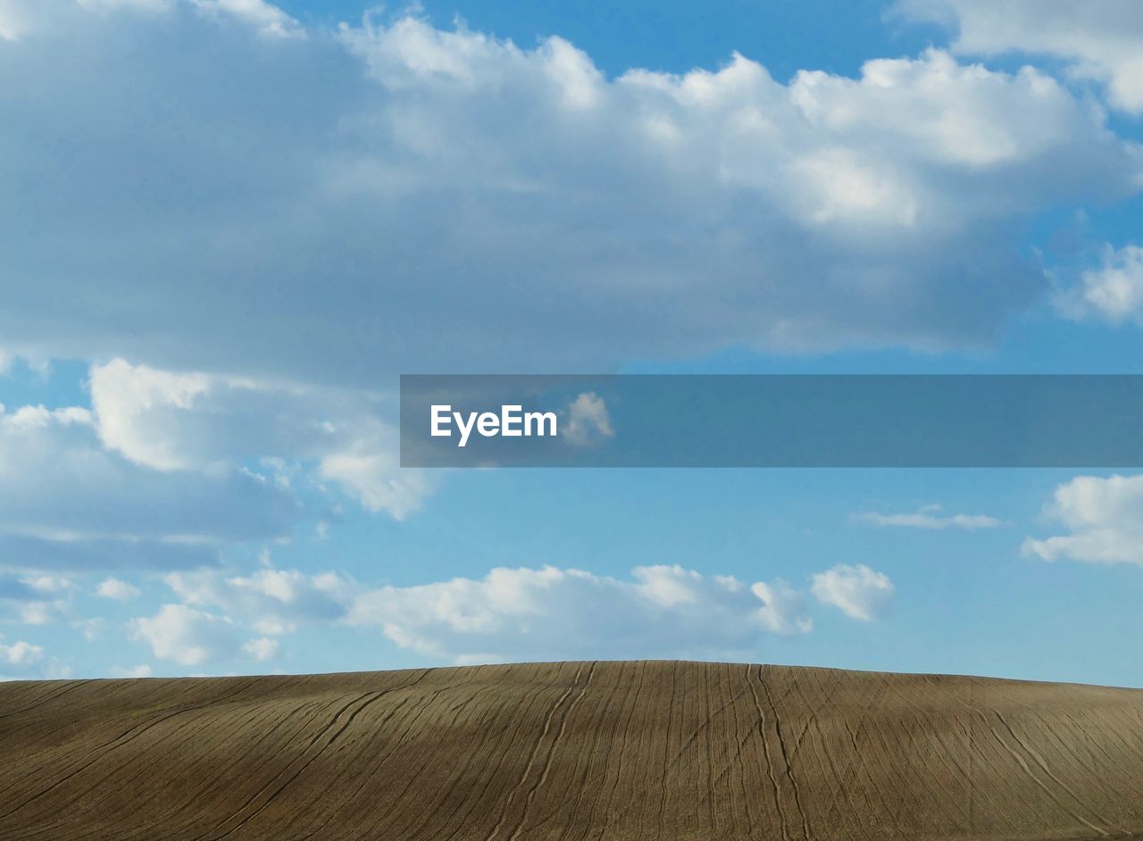 Idyllic shot of plowed field against blue sky